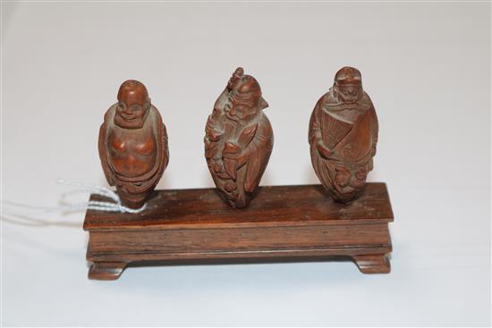 A set of six Chinese peach stones carved as immortals and a monkey, rosewood stands, each approx. height 4cm